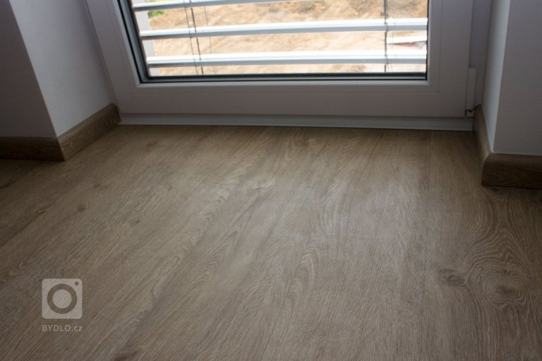 Ukončení podlahy bílou lištou u bílých balkónových dveří