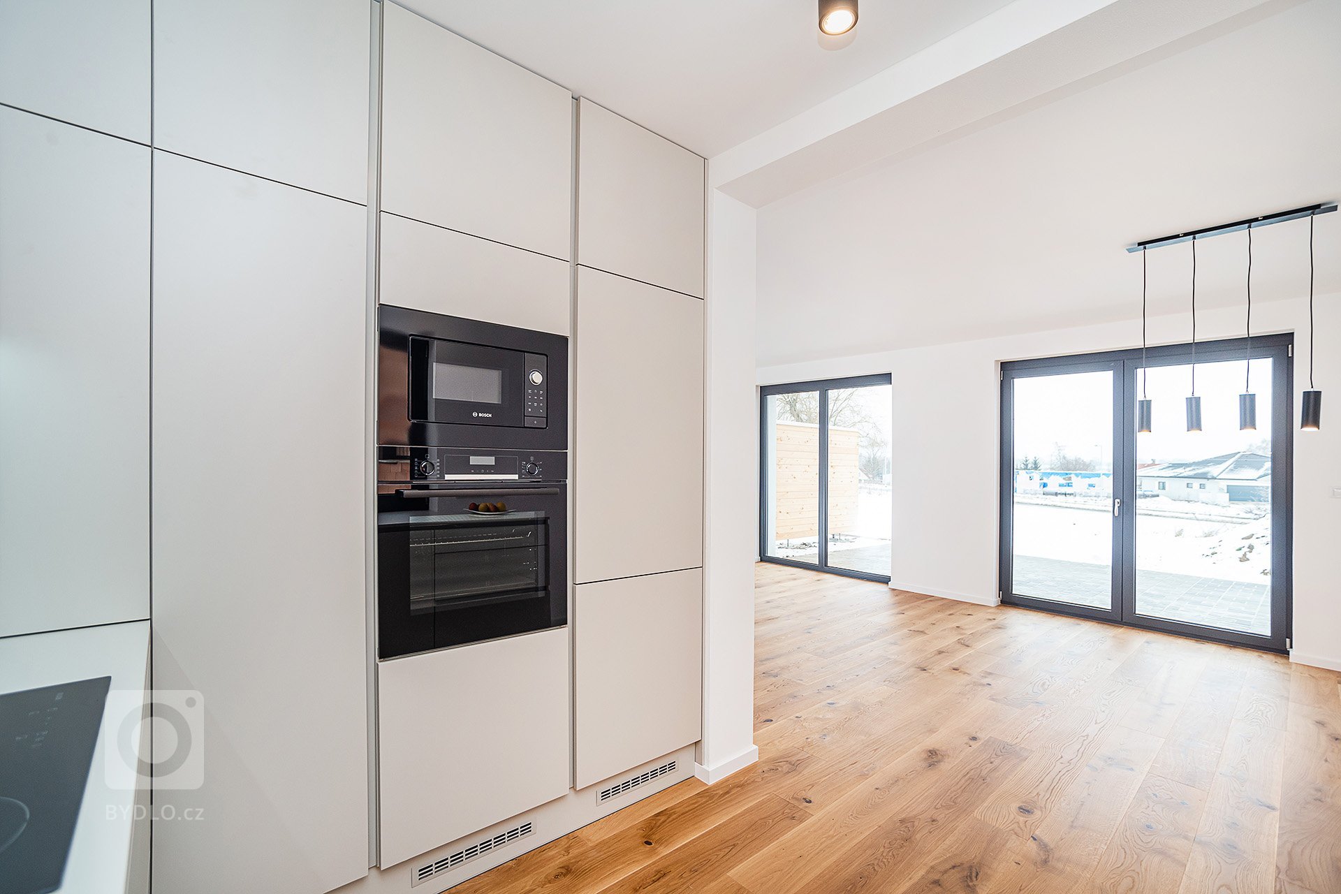 Interiér rodinného domu byl navržen v kombinaci olejovaného dubu, laminátu v odstínu taupe,&nbsp;černého lakovaného kovu a šedých odstínech velkoformátové…