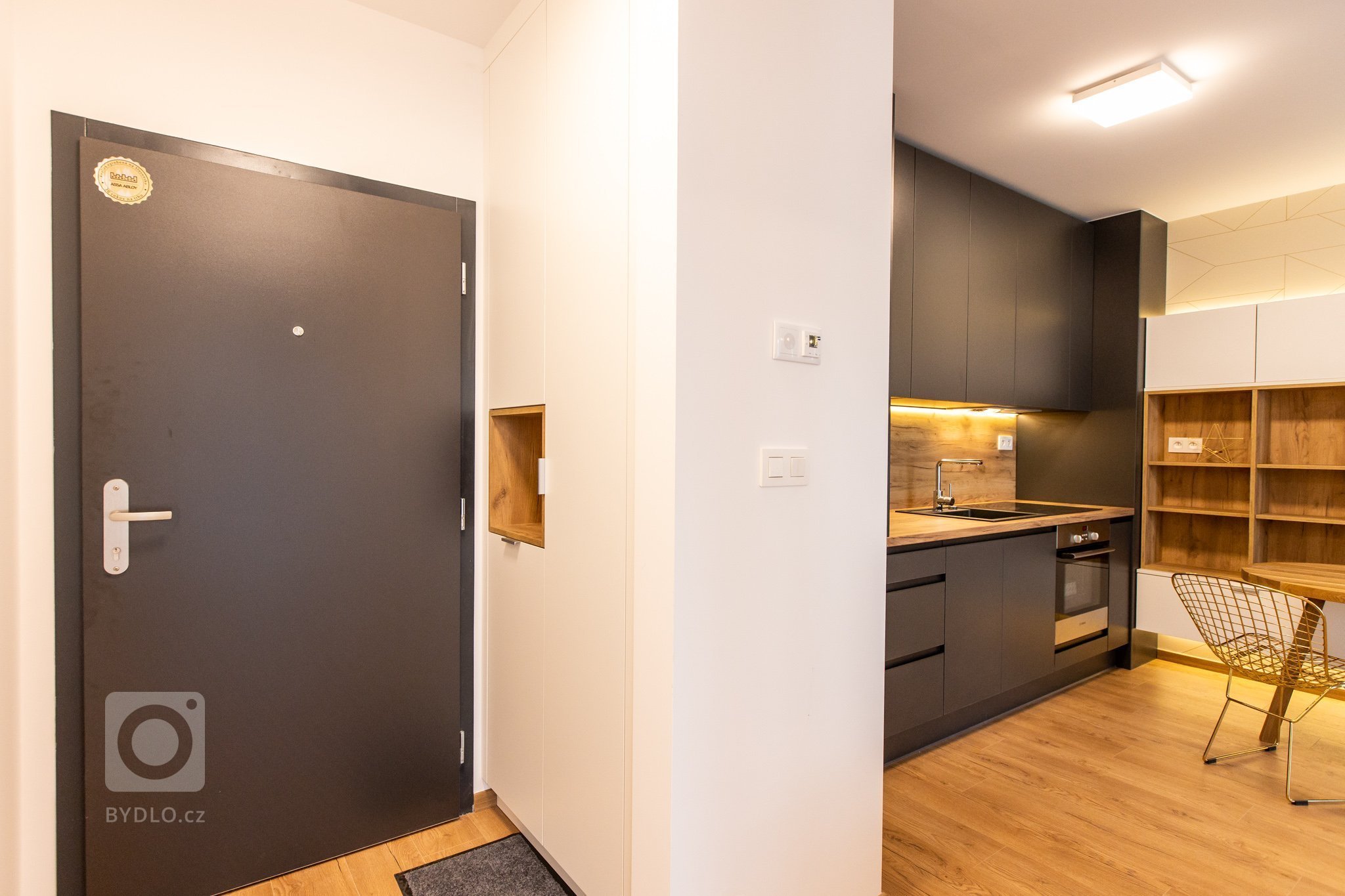 Krásna realizácia, ktorá dokonale prepája antracitovú kuchyňu s bielou obývacou zostavou.
