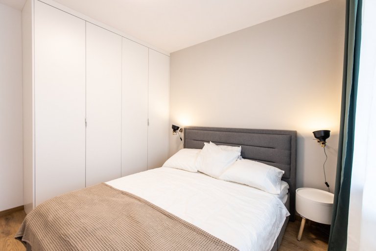 Krásne minimalisticky zariadený byt v Urban Residence, ktorého dominantou je modrá rohová sedačka. Kuchynská linka je krásne ladená v tónoch ceého bytu, aby…