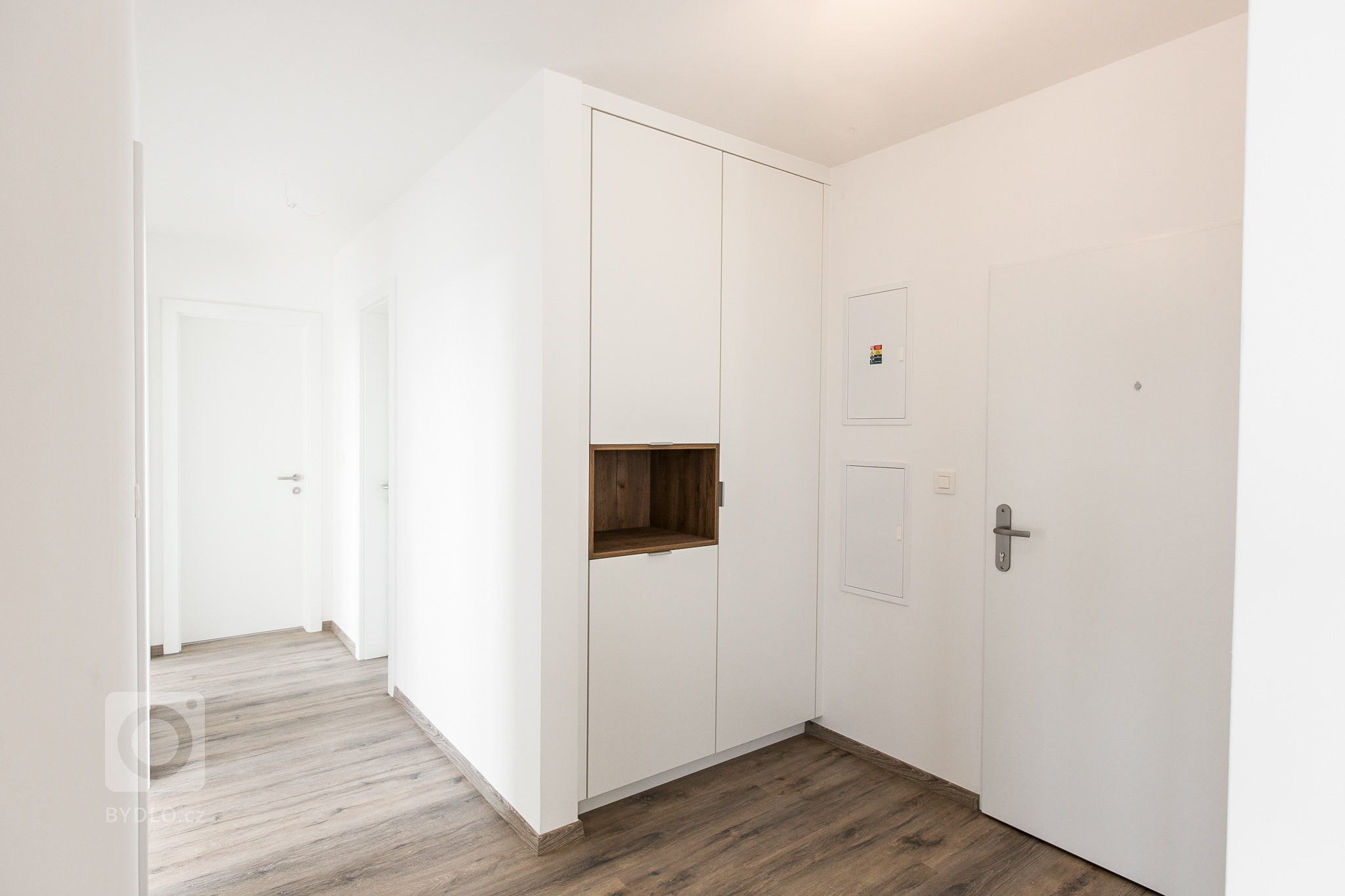 Vstavaná skriňa na chodbe s použitím rovnakých materiálov ako na kuchynskej linke