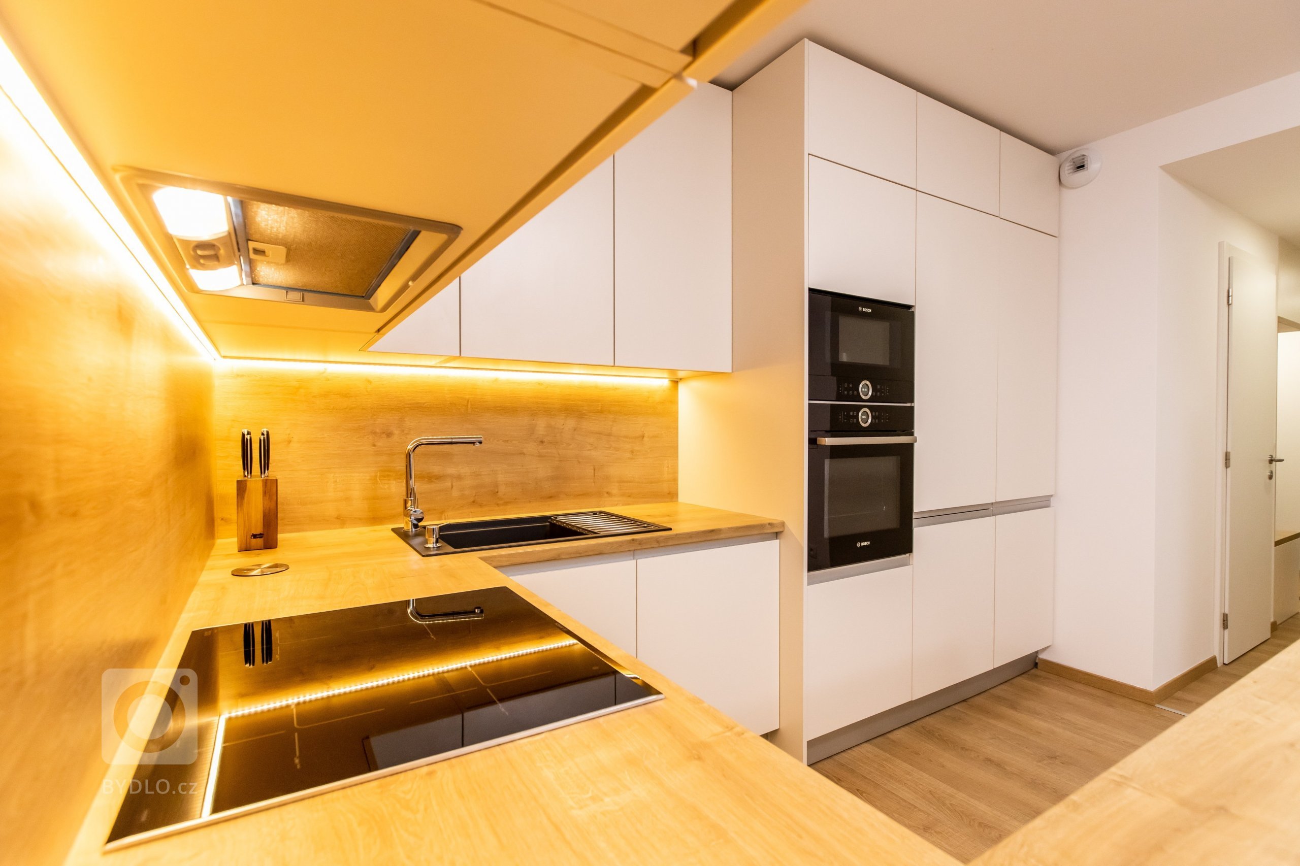 Materiály: Biely perleťový mat a Dub zlatý

Podsvietenie: Teplý&nbsp;LED pás

Madlá: Kuchyňa - Zafrézované hliníkové

Skrine - Madlo v tvare &quot;L&quot…