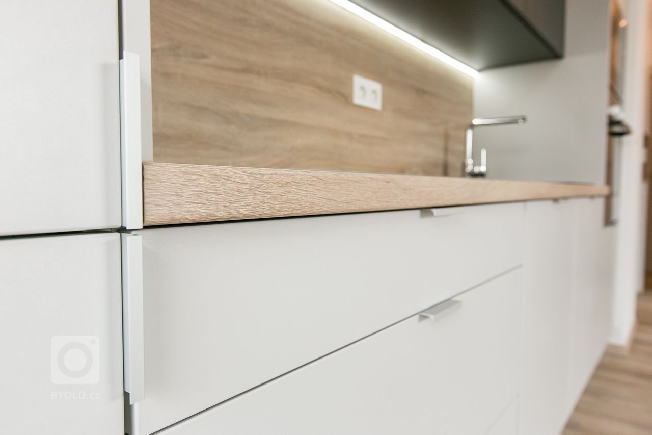 Použité materiály:

Horné skrinky: antracitový mat
Dolné a vysoké skrinky:&nbsp;biely perleťový mat
Vstavané skrine: biely perleťový mat
Výklenok: dub…