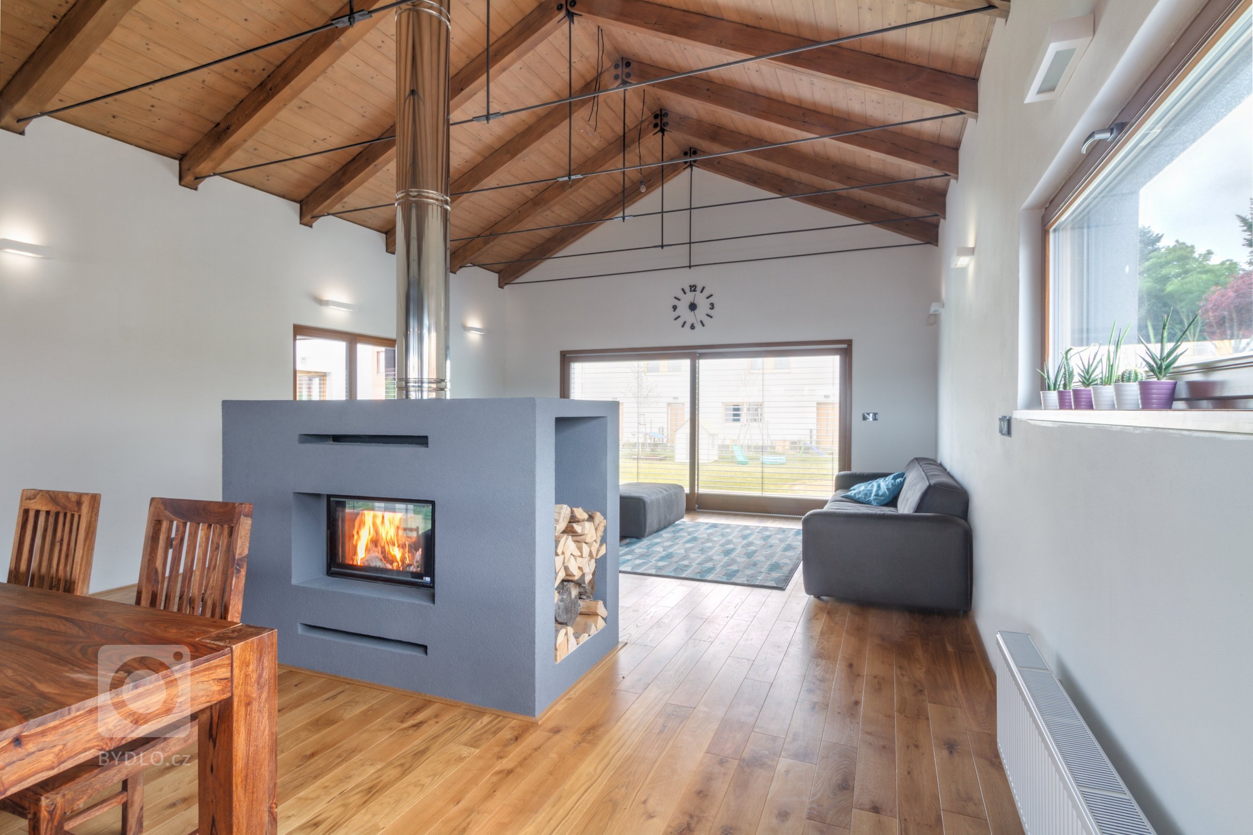 Dům je umístěn v severní části pozemku a otevírá se velkým francouzským oknem a atriem na jih do zahrady. Svou formou - tvarem střech a velikostí hmot -…