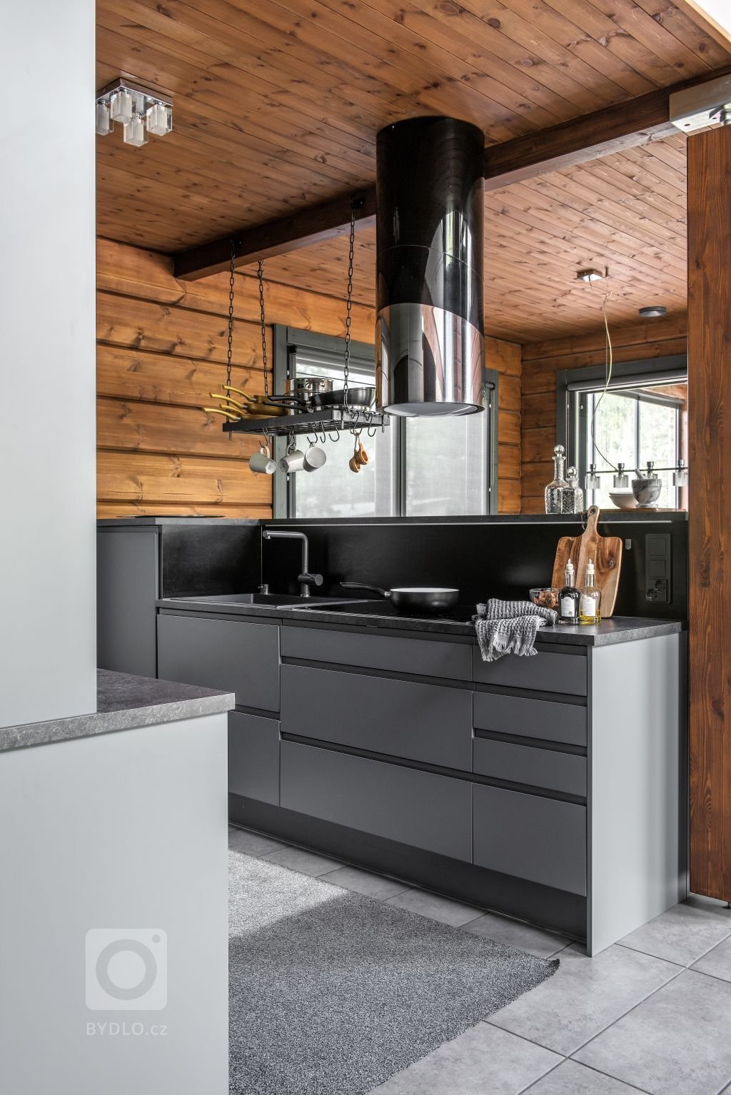 Kuchyňský ostrůvek sestává z šedé kuchyňské linky. Dřez, který je také v krásné šedé barvě s linkou téměř splývá. Černý kuchyňský kohoutek dodává eleganci. Dále je součástí linky sporák a ergonomicky umístěná integrovaná myčka. Kovová police zavěšená ze stropu nad dřezem je dílem místního kováře, na které se dá zavěsit nejpoužívanější kuchyňské náčiní. 