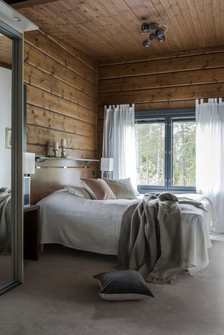 Struktura trámových stěn přispívá k atmosféře luxusu v hlavní ložnici stejně jako šedo-béžový koberec, sametové polštáře a mohérový přehoz.