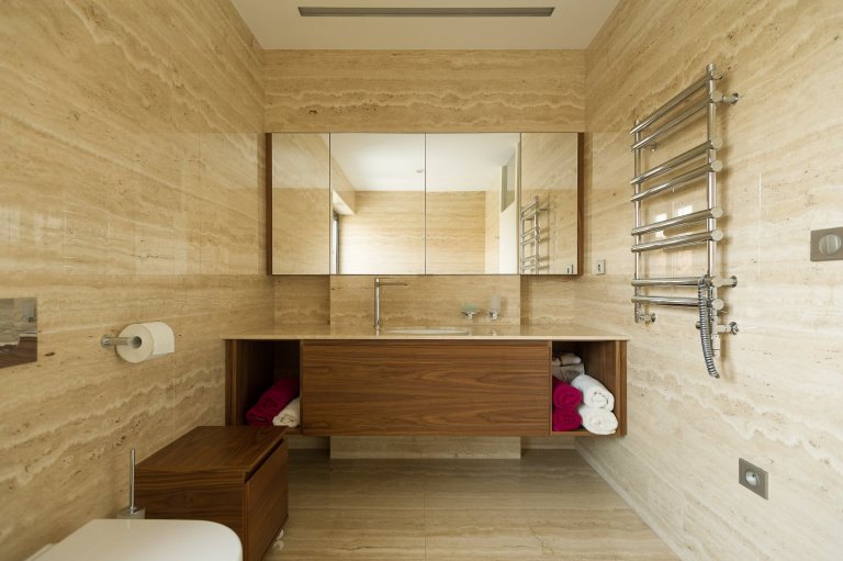 Koupelna obložena velkoformátovými travertinovými obklady.