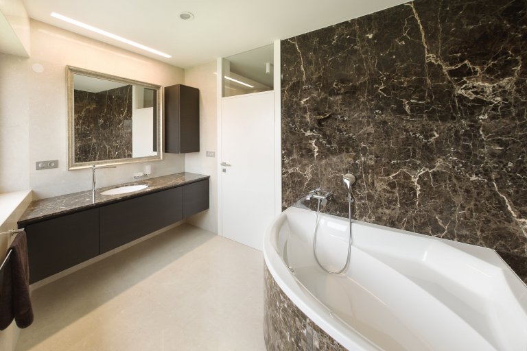 Pánská koupelna s velkoformátovými kamennými obklady.