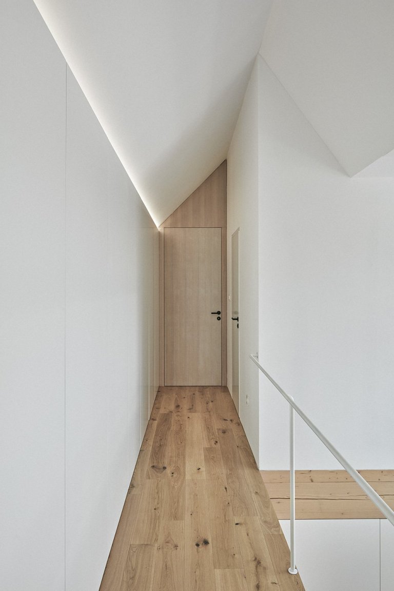 Pozemek leží na hraně svahu v&nbsp;centru malé obce na Vysočině. Na půdorysné stopě bývalého statku vznikl dům a stodola. Dům má podél jihozápadní fasády kryté…