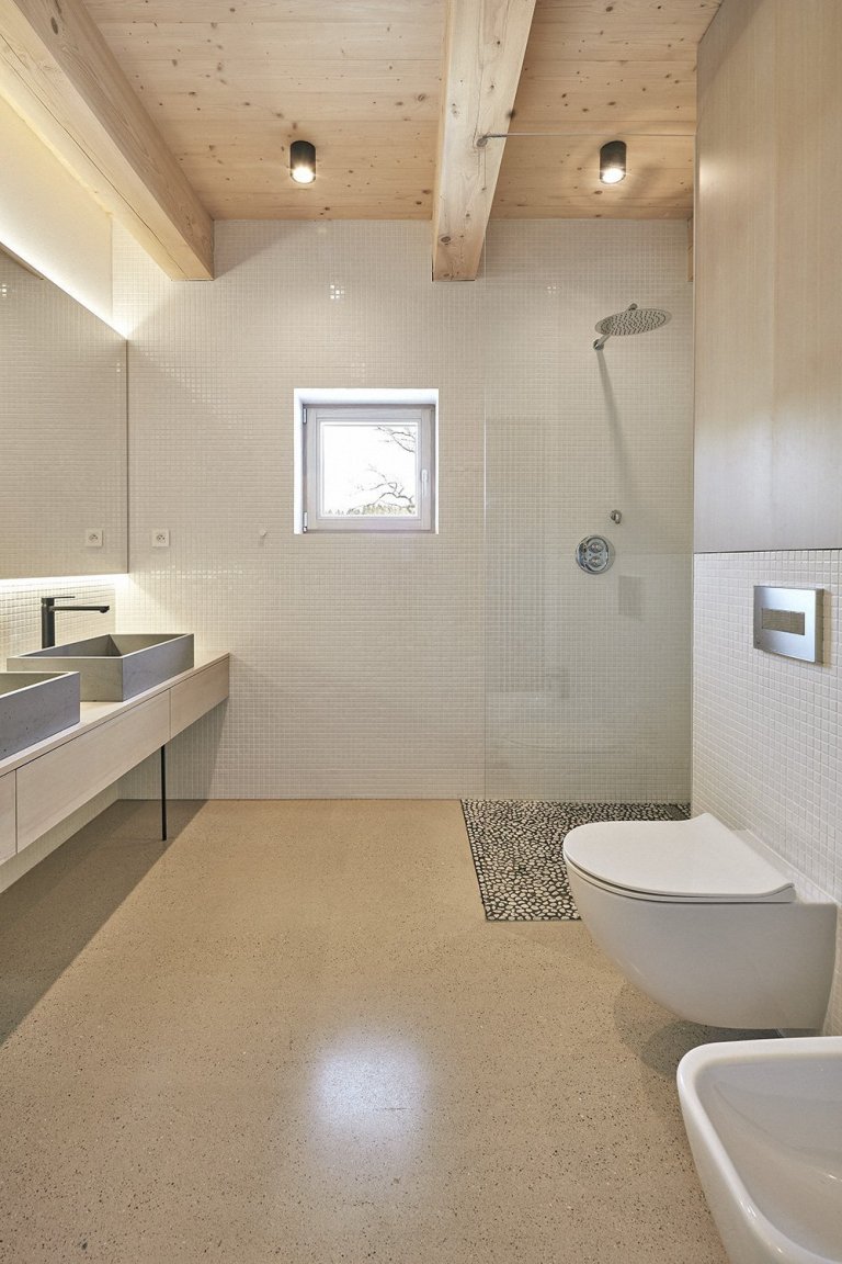 Pozemek leží na hraně svahu v&nbsp;centru malé obce na Vysočině. Na půdorysné stopě bývalého statku vznikl dům a stodola. Dům má podél jihozápadní fasády kryté…