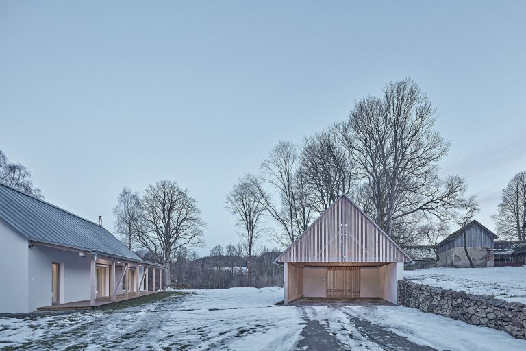 Pozemek leží na hraně svahu v&nbsp;centru malé obce na Vysočině. Na půdorysné stopě bývalého statku vznikl dům a stodola. Dům má podél jihozápadní fasády kryté…
