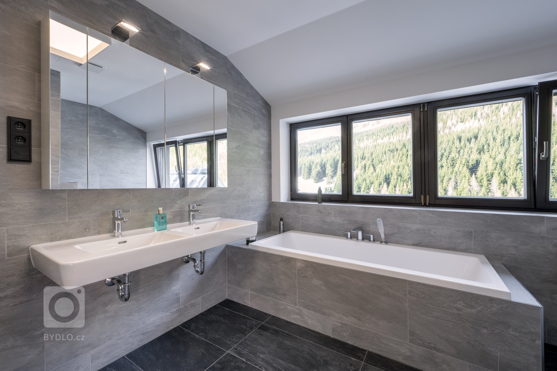 Koncept interiéru je laděn do přírodních materiálů a tmavších barev v&nbsp;kombinaci s&nbsp;bronzem, alcantarou a koňakovou kůží. Podlaha je až na koupelny…