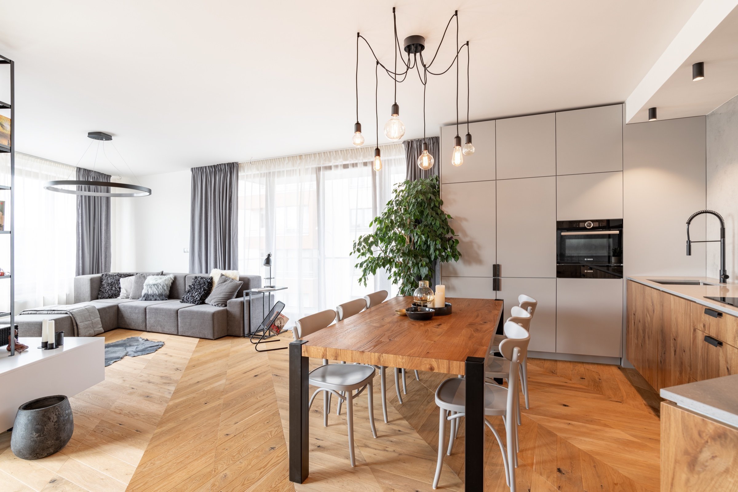 Součástí obývacího pokoje je kuchyňská linka a jídelní stůl. Tento otevřený koncept perfektně propojuje veškeré materiály dohromady.