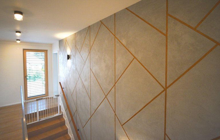Realizace dekorativních aplikací v geometrickém designu. Reliéfní betonová stěrka se spárou probarvenou v měděnné metaléze, dále dekorativní šablonová malba a…
