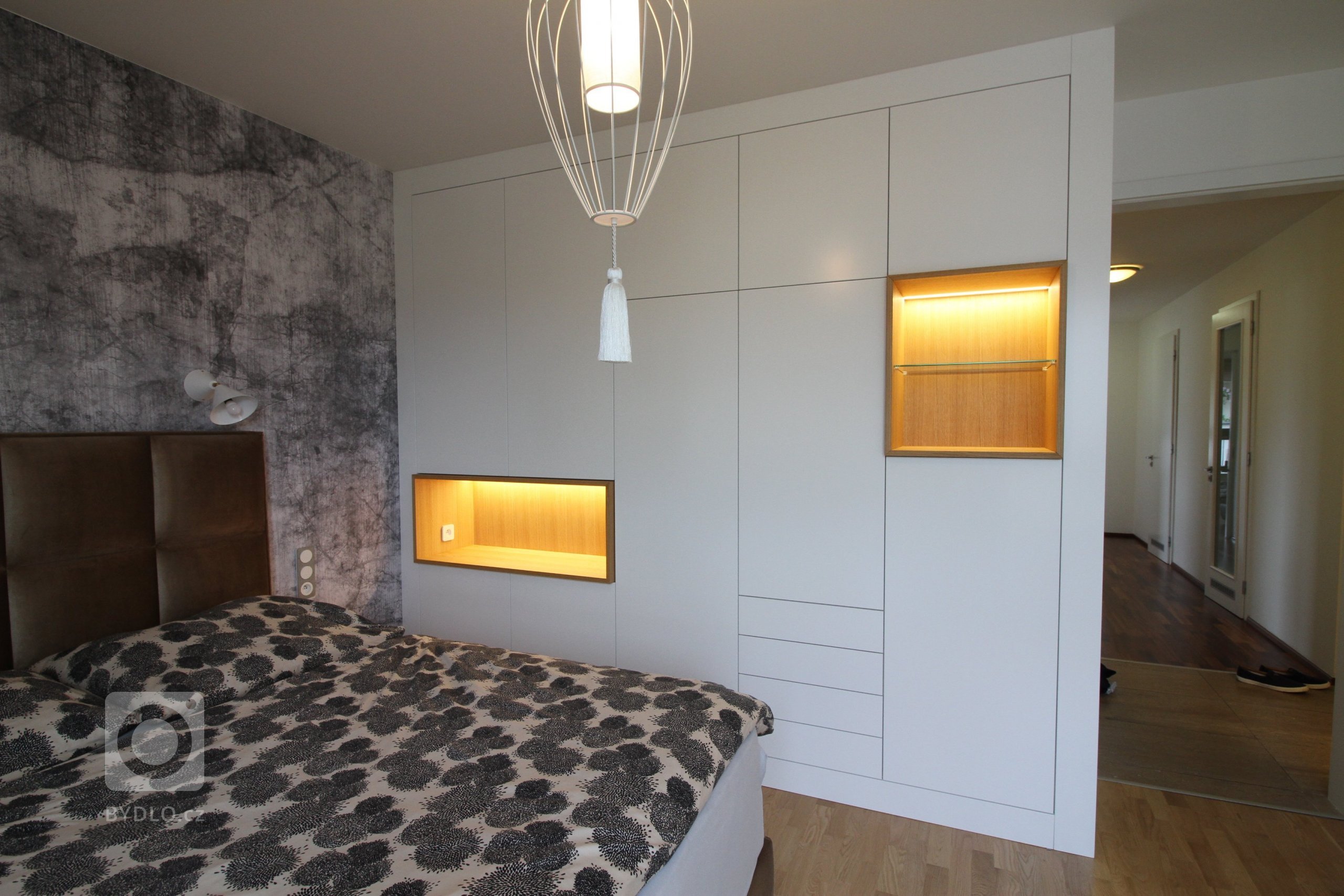 Interiér ložnice s italskou tapetou a svítidly, šatní skříň podle autorského návrhu.

