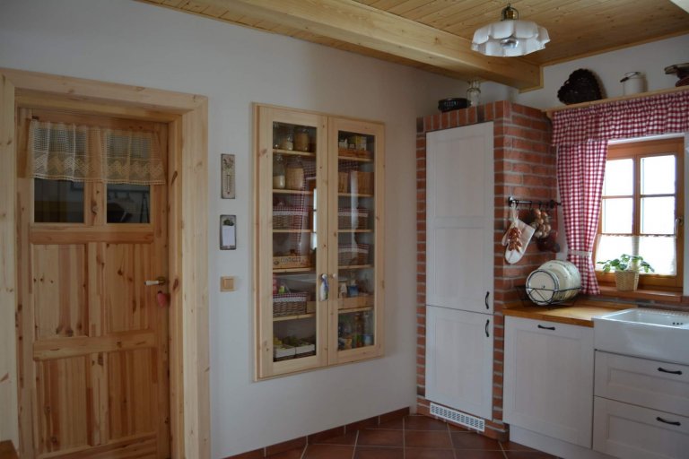 Prostorná rustikální kuchyně s&nbsp;moderními spotřebiči, doplněna památečnými kousky (formy, mlýnky, ošatky atd.) a cihlovým obkladem pro navození požadované…