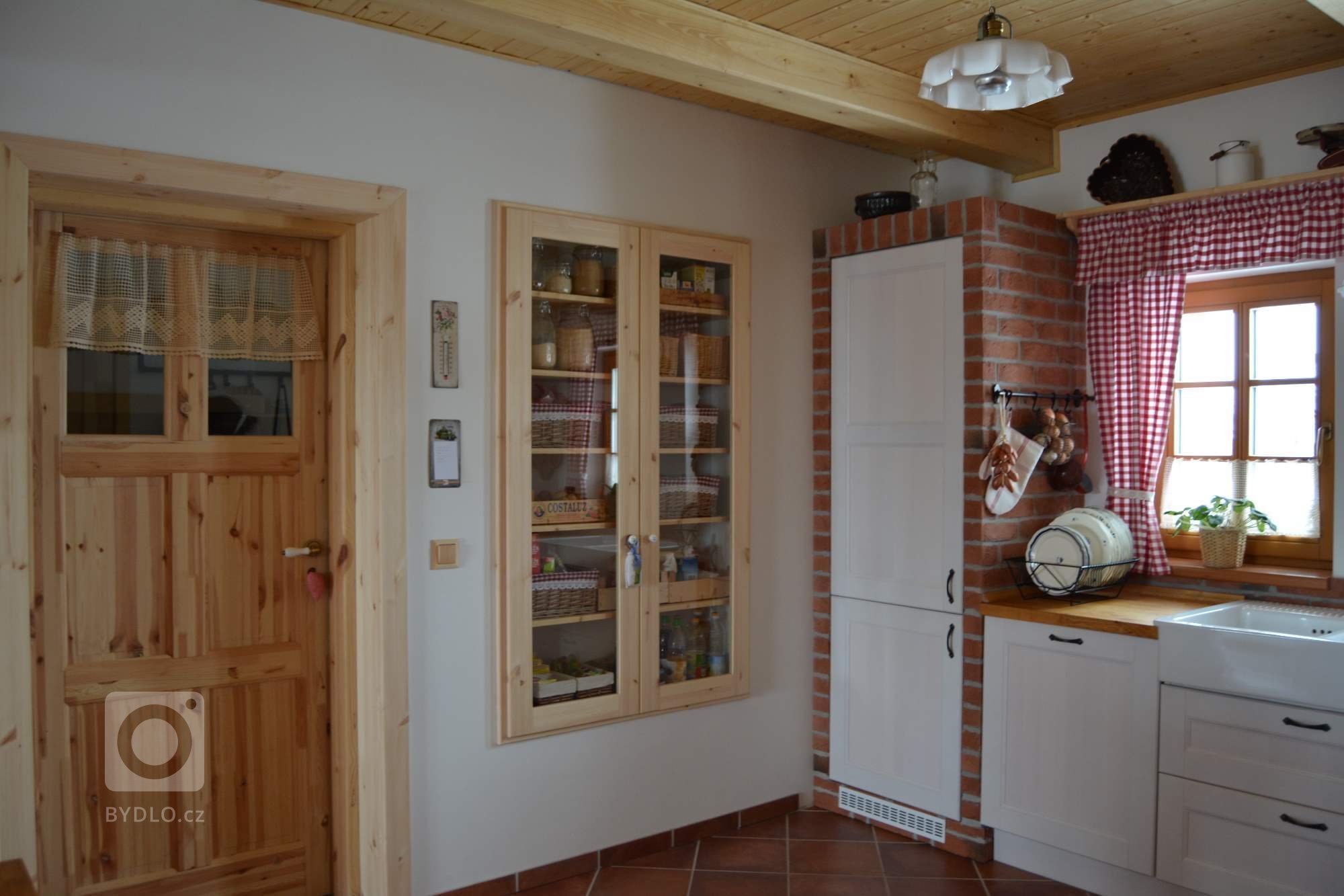 Prostorná rustikální kuchyně s&nbsp;moderními spotřebiči, doplněna památečnými kousky (formy, mlýnky, ošatky atd.) a cihlovým obkladem pro navození požadované…