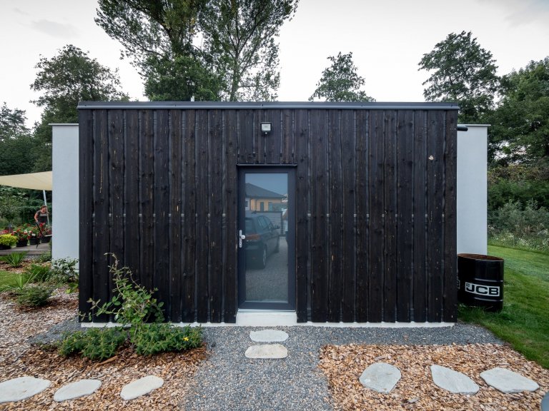 Základní hmotu domu ZEN HOME doplňuje přístavba z černých nesámovaných prken.