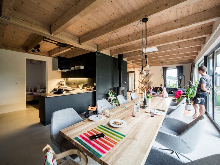 Obytný prostor ZEN HOME, osvědčená kombinace betonové podlahy, dřevěného stropu, černé stěrky i kuchyně a velkého prosklení.