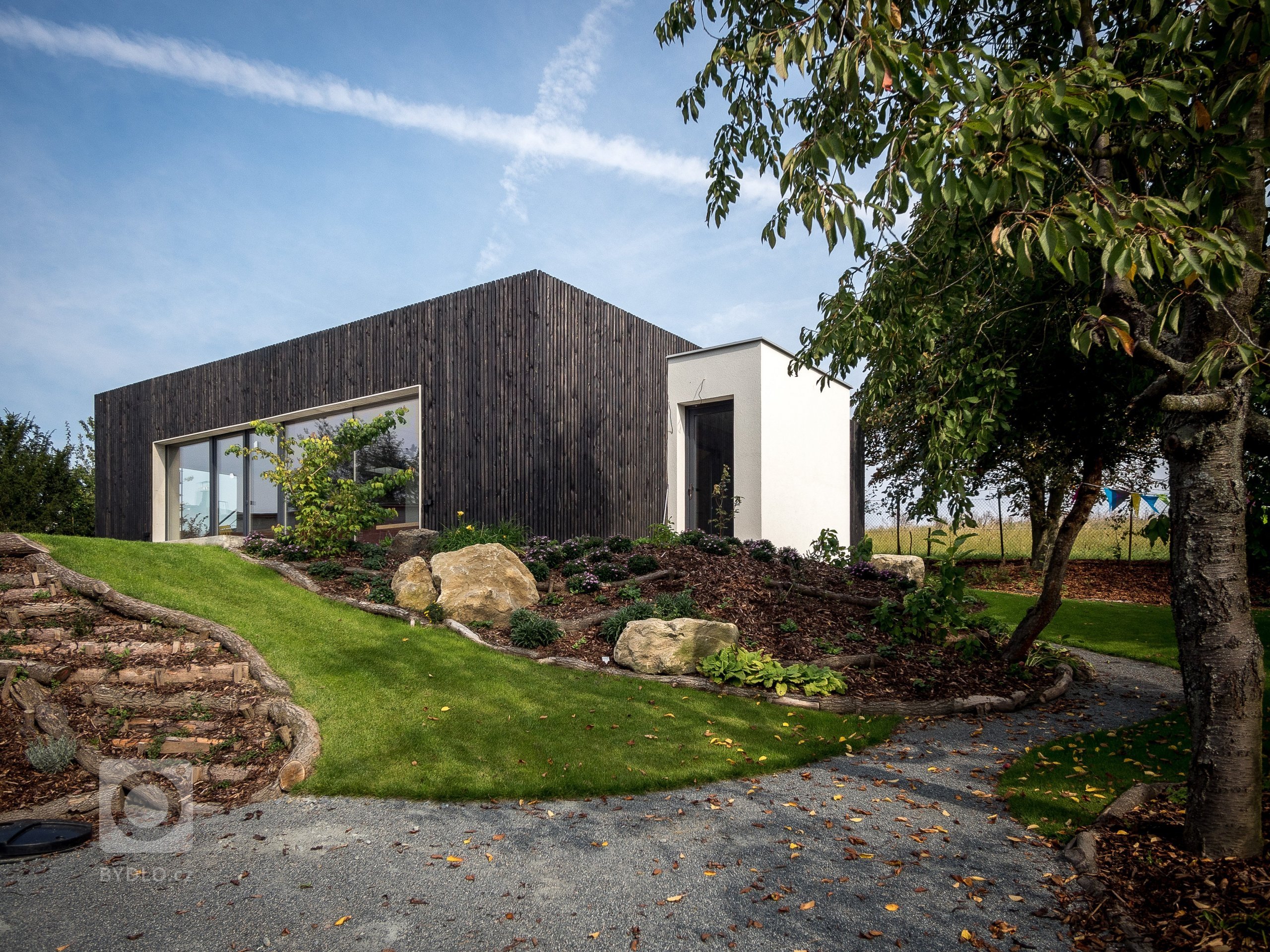 Dům ZEN HOME v podobě kvádru s černou dřevěnou fasádou je doplněn malou přístavbou vstupní haly v bílé omítce.