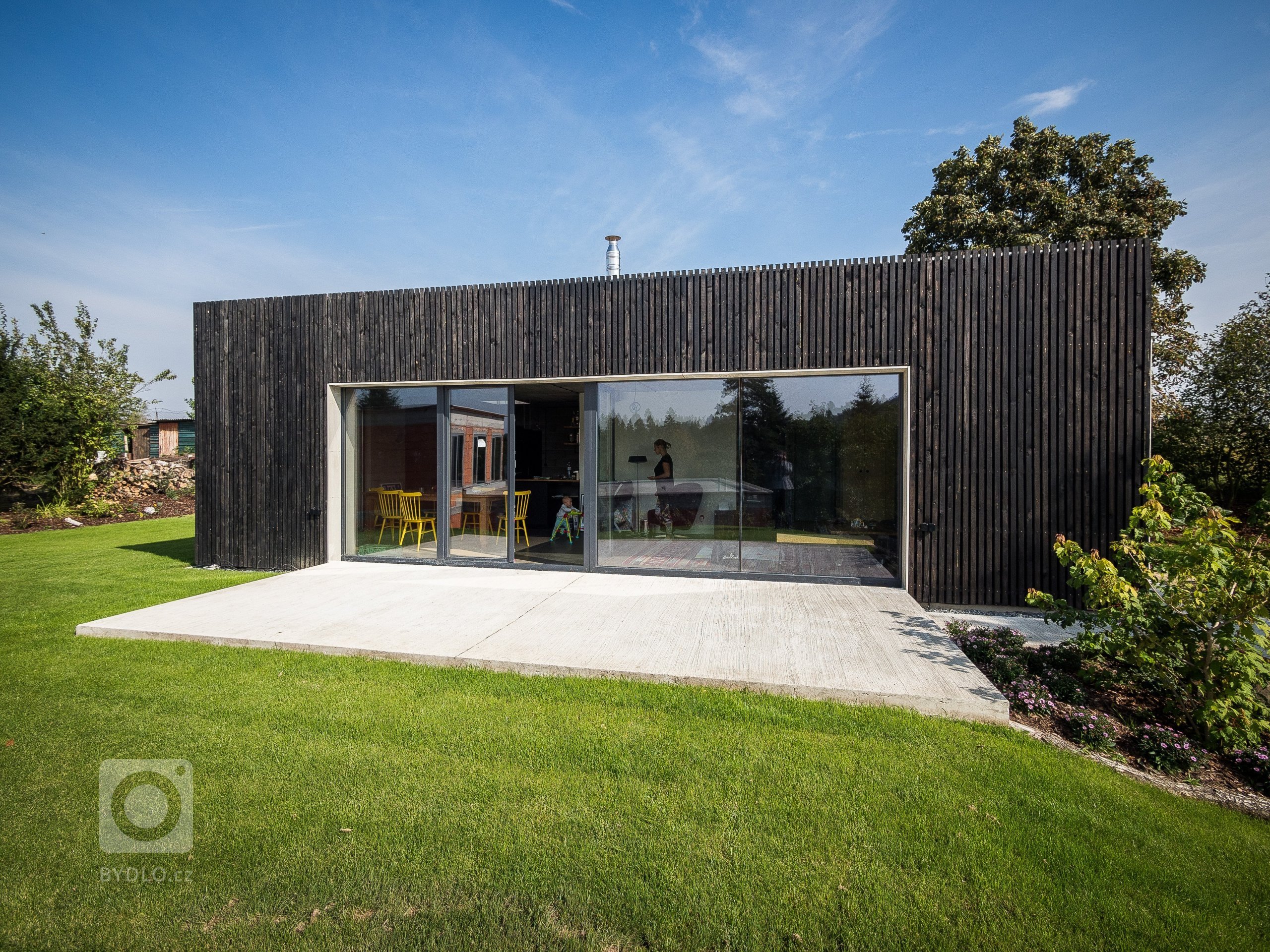 Jednoduchou hmotu ZEN HOME zdobí fasáda z hrubého černého dřeva a velké prosklení.