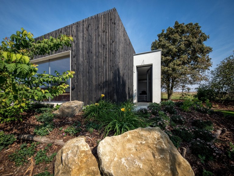 ZENHOME kousek od Prahy je na skvělém vyvýšeném místě uprostřed zeleně. Strohý kvádr zdobí fasáda z černého nehoblovaného dřeva a velké prosklení s bezrámovými…